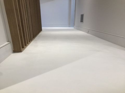 Smooth, bright microcement floor finish in a modern hallway